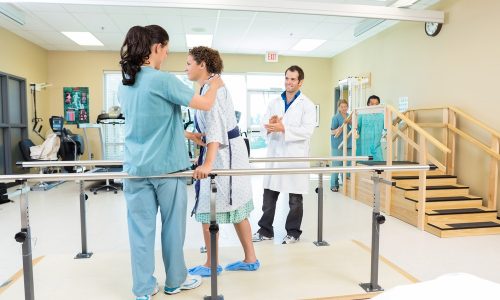 Mid,Adult,Female,Patient,Being,Assisted,By,Physical,Therapist,While